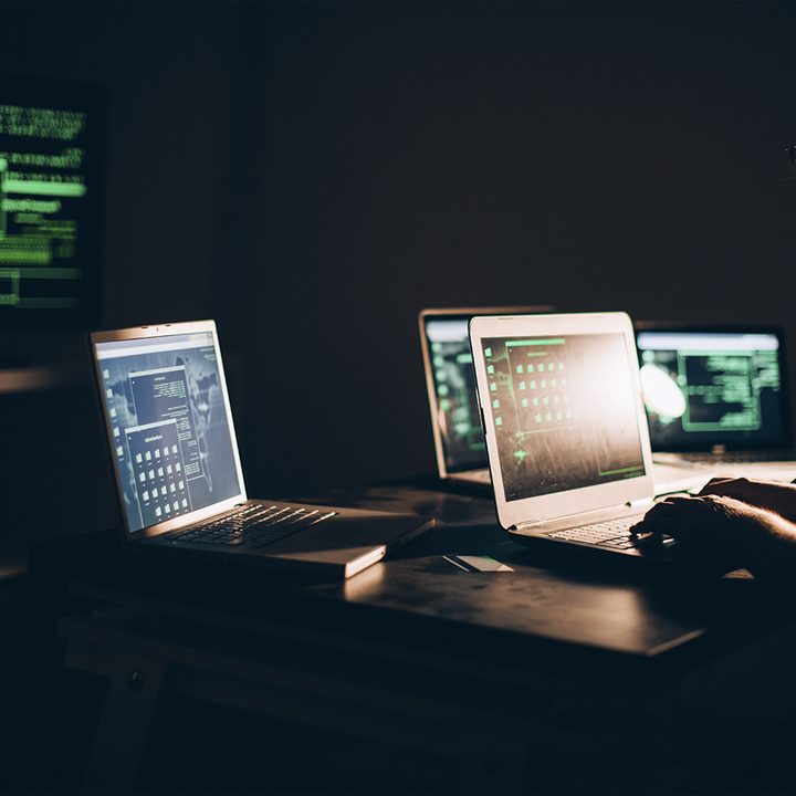 A person surrounded by several computers types on a laptop.