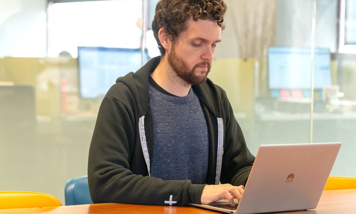A person typing on a Huawei MateBook X Pro laptop at a table.