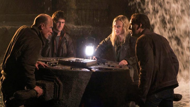 Four people stand around a table.