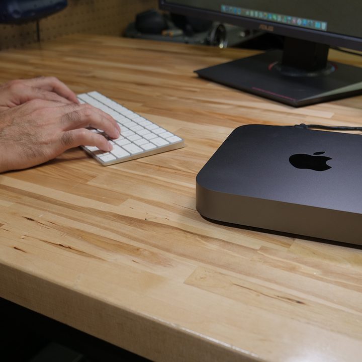 The Apple Mac Mini being used on a wooden desk.