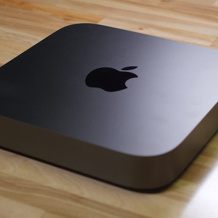 An Apple Mac Mini sits on a wooden table.