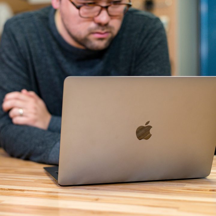A person working at a 2018 Macbook Air at a wooden table.
