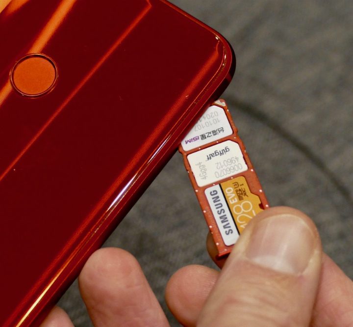 A SIM card next to a smartphone.