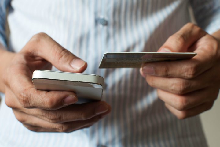 An individual holding a phone and card.