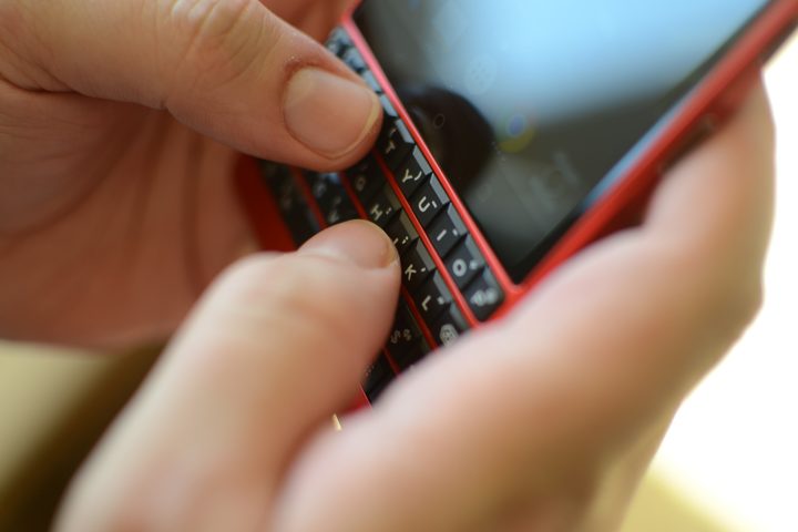 Close up of someone typing on a Blackberry keyboard.