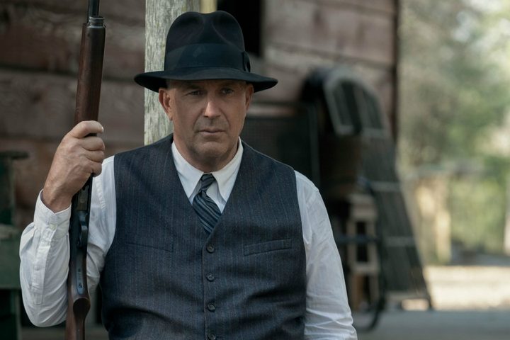 Kevin Costner wields a shotgun and stares.