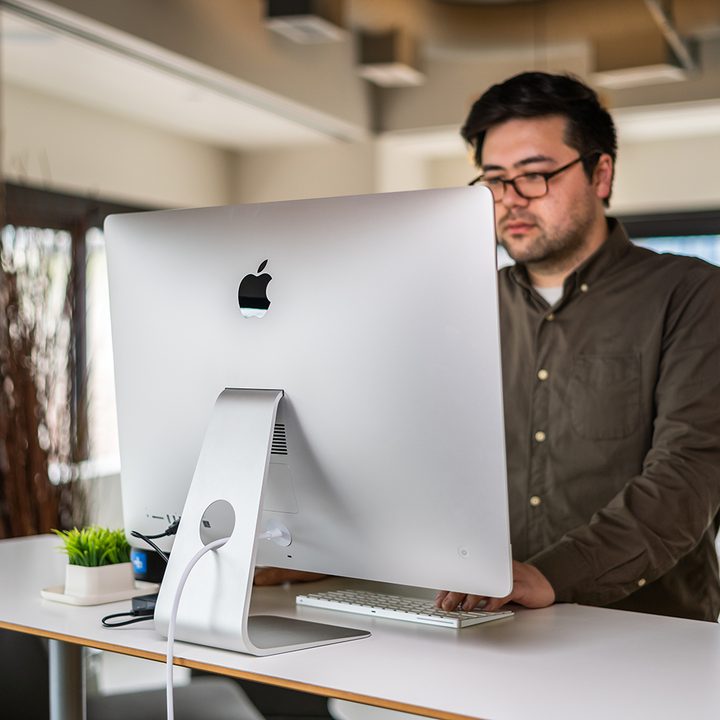A person using a 27-inch iMac on a desk.