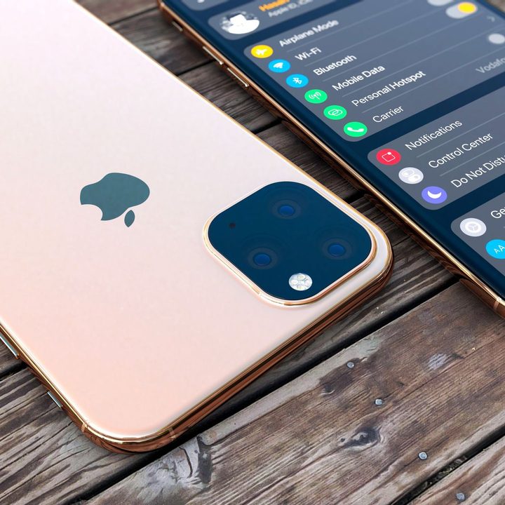 Two iPhones, one face up and one face down on a wooden table.