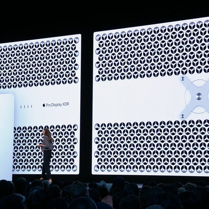 A person onstage at an Apple event with two Pro Display XDR monitors behind them, with the rear of the monitors in view.