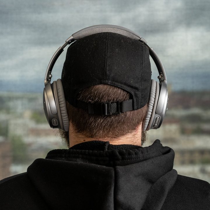 A dude in a baseball hat wearing Bose Quiet Comfort 35 II.