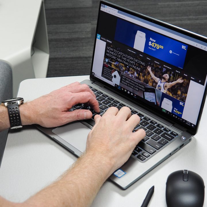 Two hands typing on a Dell Latitude 7400 2-in-1 laptop.