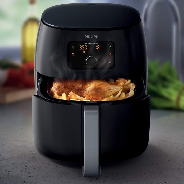 A black Philips Digital Twin TurboStar Air Fryer XXL containing air-fried chicken and french fries.