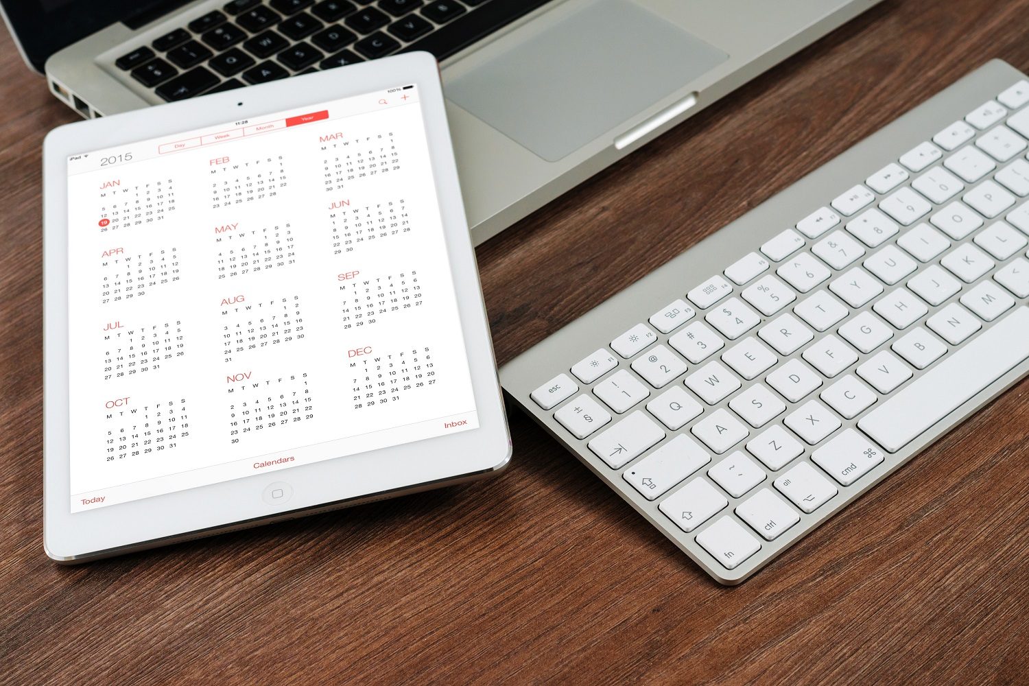 calendar on iPad next to macbook and mac keyboard