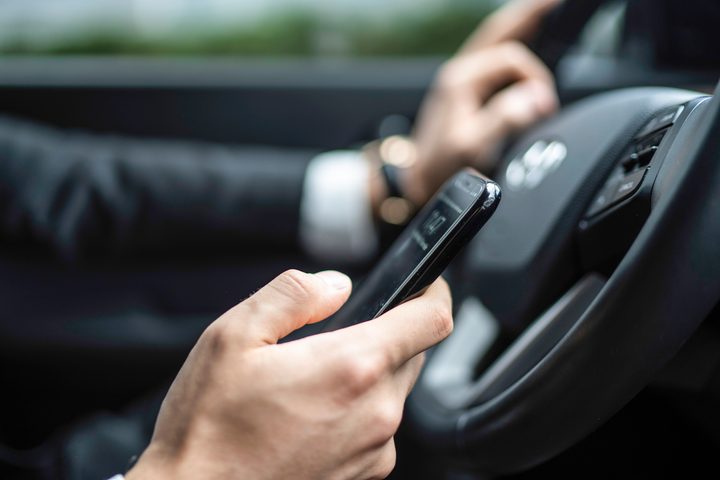 Man texting while driving car