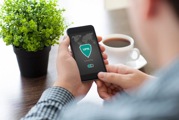Man holding phone running VPN to browse anonymously.