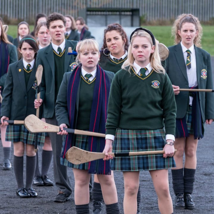 A group of school girls stand in a line with paddles.