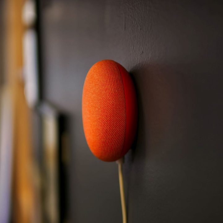 A red Nest Mini mounted to a wall.