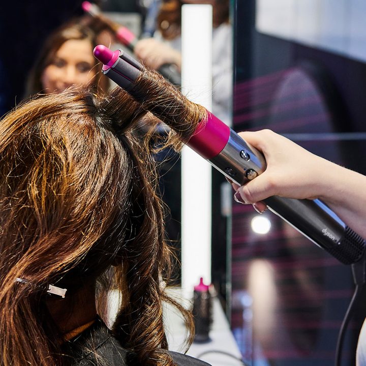 Woman using Dyson Airwrap on another woman's hair.