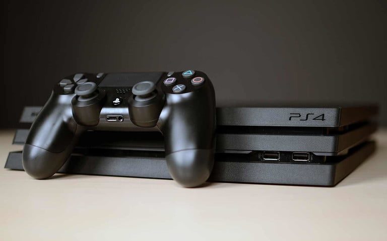 A PS4 Pro sitting on a table with a controller.