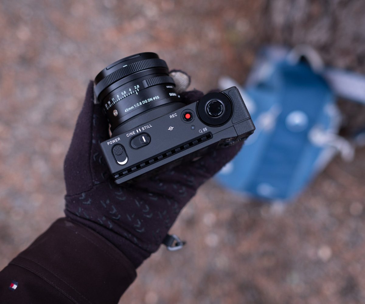 Sigma fp in hand showing top plate and 45mm f/2.8 lens.