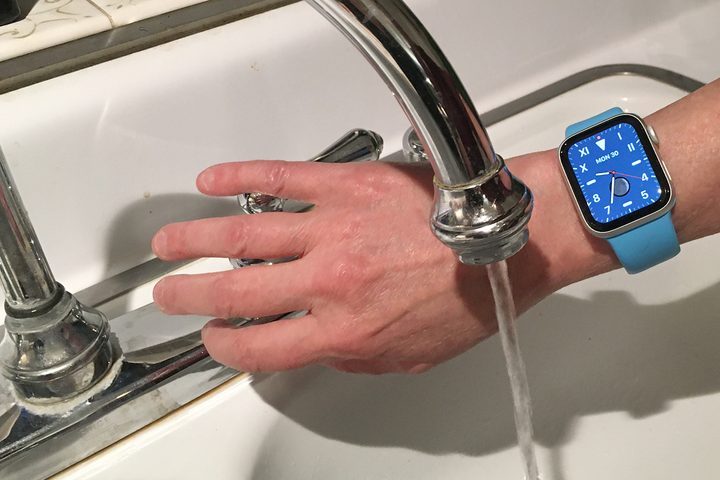 An Apple Watch being held near to the water.
