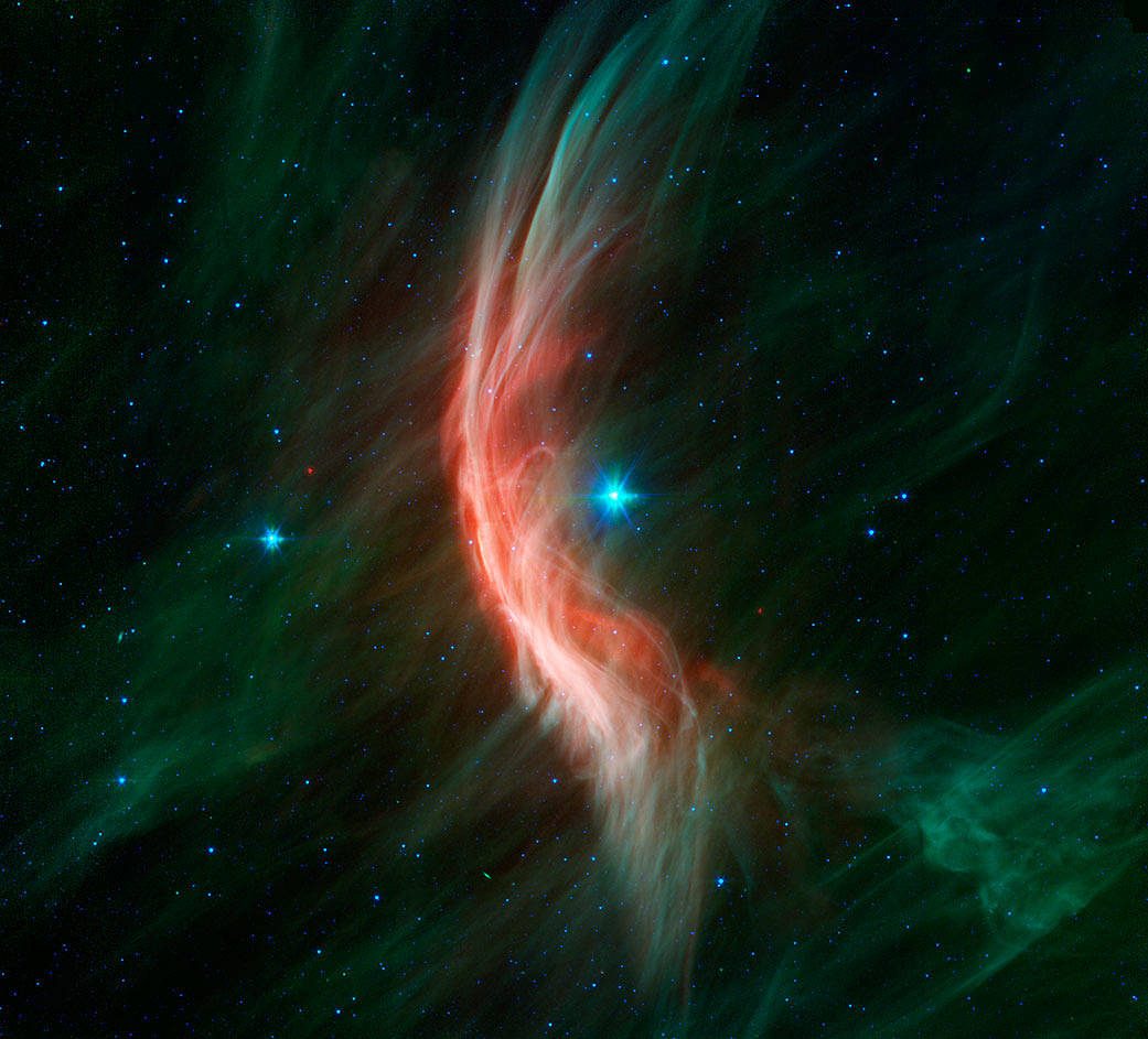 This Spitzer image shows the giant star Zeta Ophiuchi and the bow shock, or shock wave, in front of it. Visible only in infrared light, the bow shock is created by winds that flow from the star, making ripples in the surrounding dust.