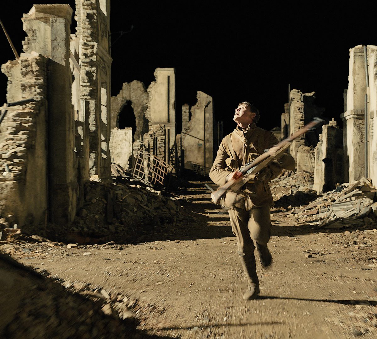 George MacKay as Schofield running through ruins of a bombarded city.