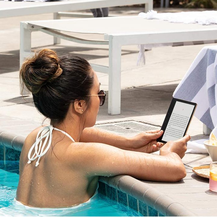 A woman reading an e-book on the Amazon Kindle Oasis while in a swimming pool.