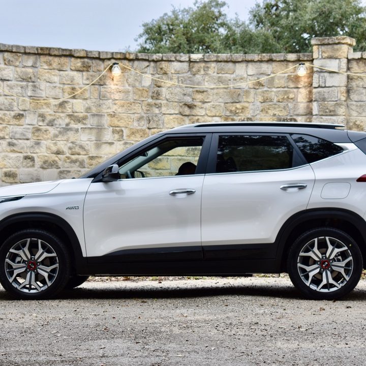 A silver 2021 Kia Seltos in front of a stone wall.