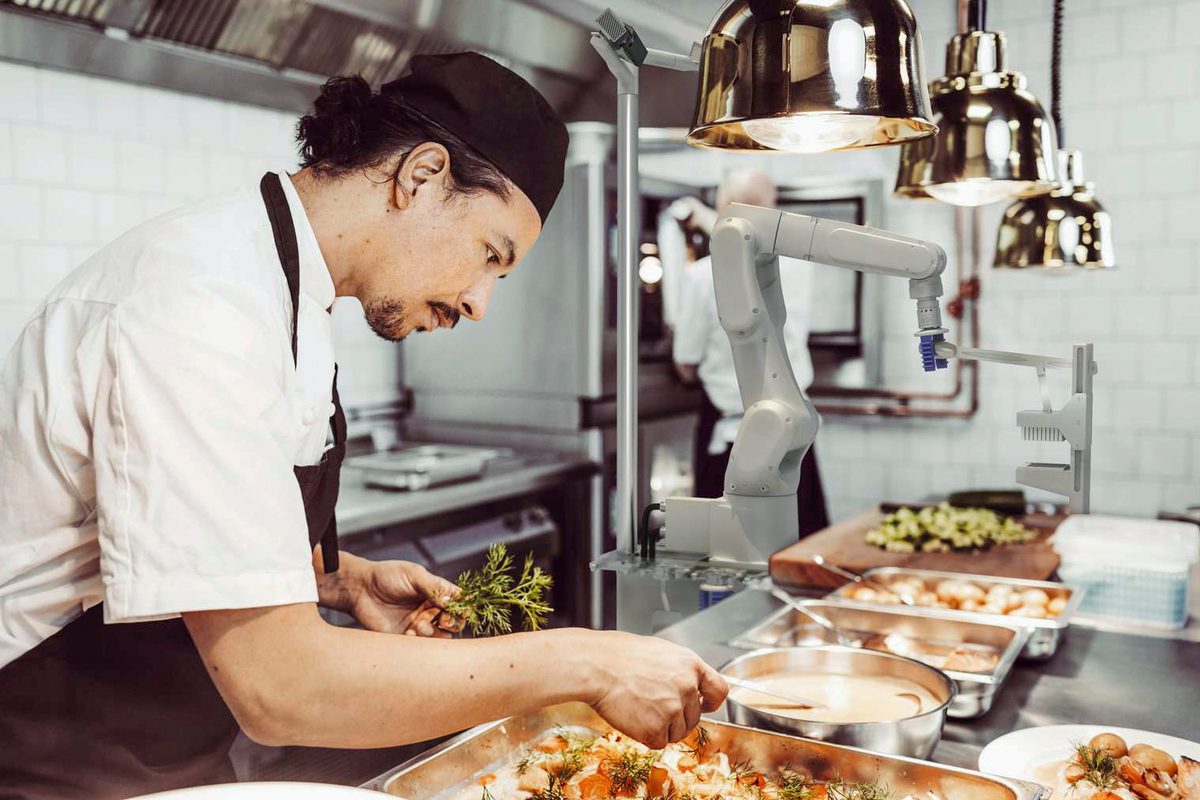 Flippy assisting a chef in a kitchen with salad making