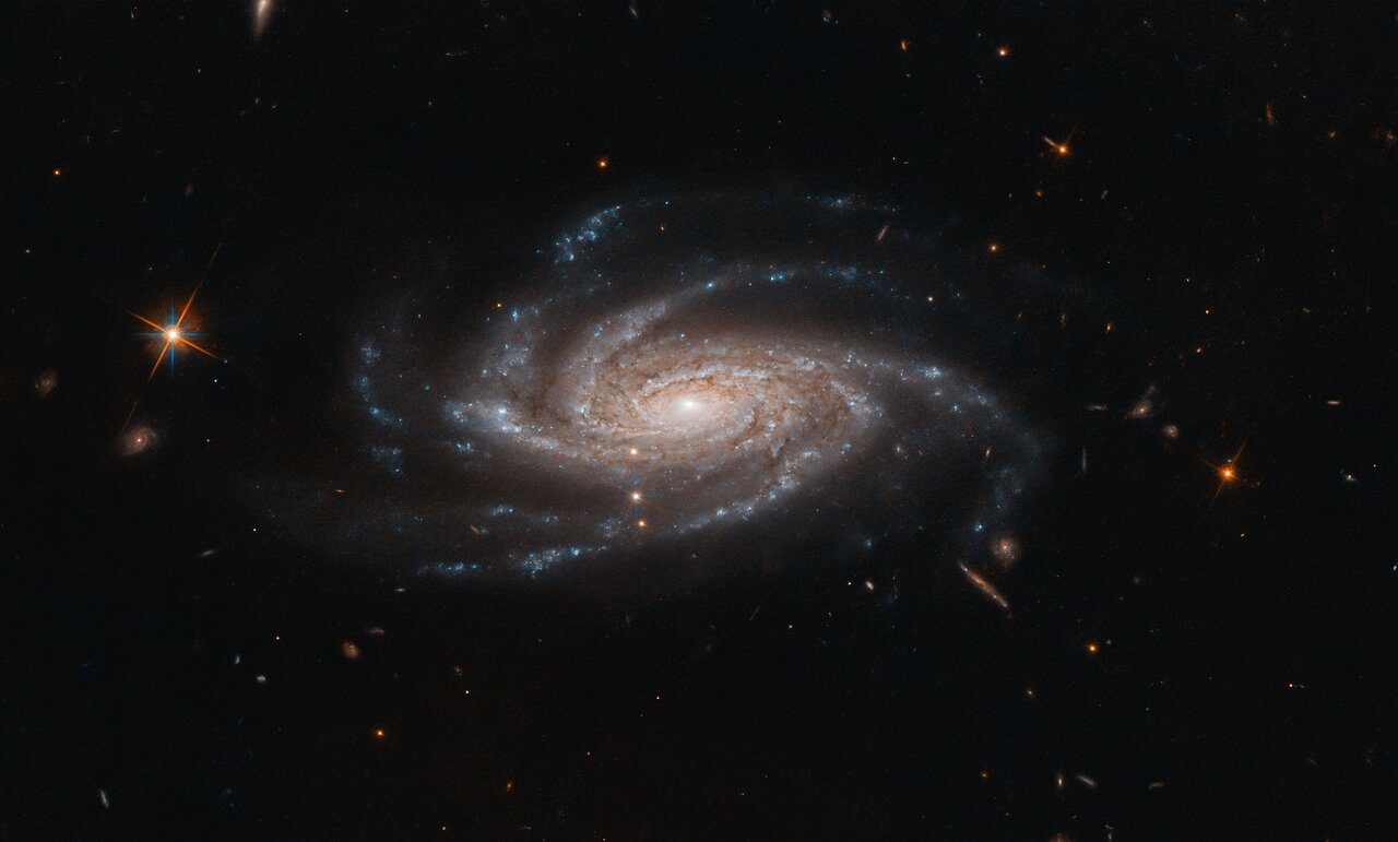 The spiral galaxy NGC 2008 sits centre stage, its ghostly spiral arms spreading out towards us, in this image captured by the NASA/ESA Hubble Space Telescope.