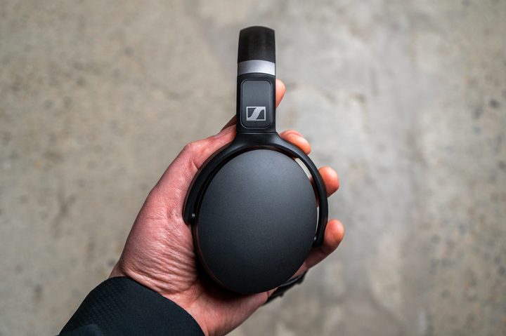 Holding the Sennheiser HD 450BT headphones.