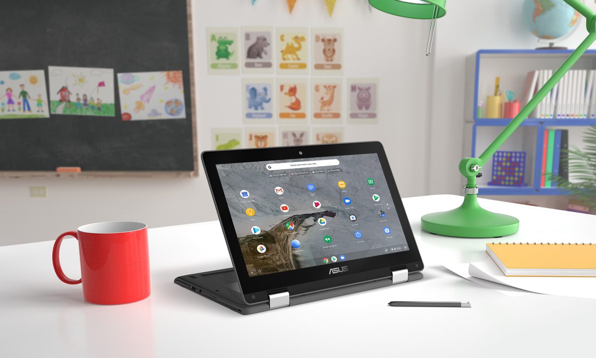 ASUS Chromebook Flip C214 sitting on a desk in a classroom.