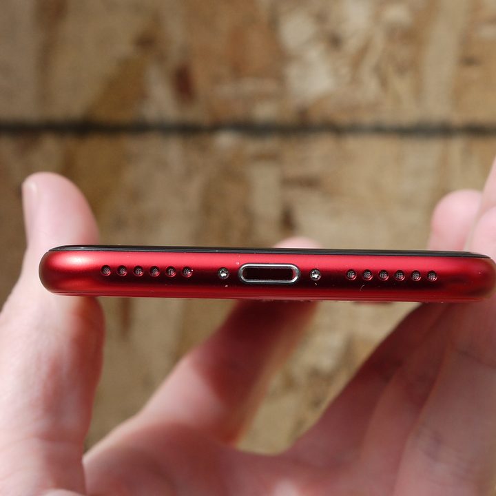 The bottom of a red iPhone SE.