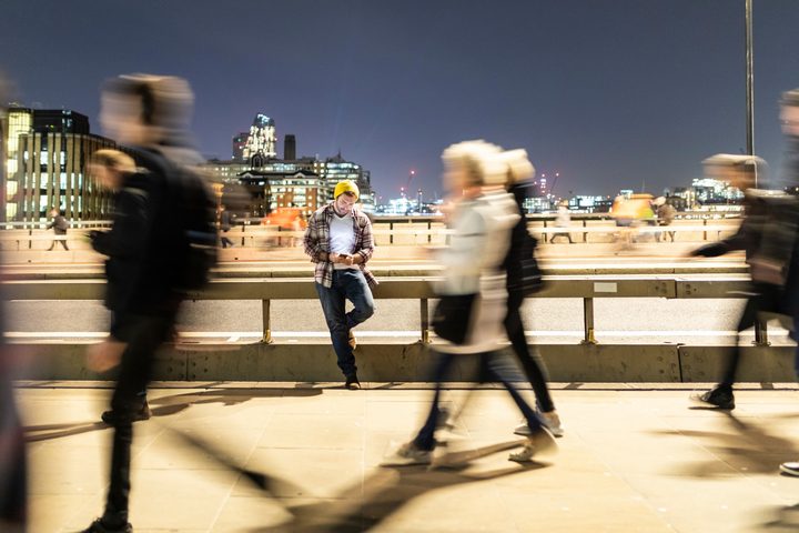 Man sitting on rail as people walk by