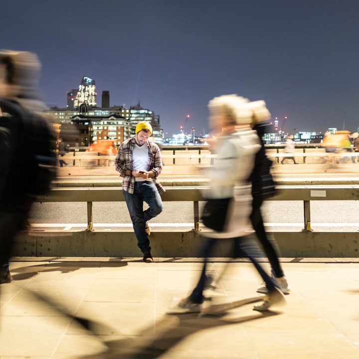 Man sitting on rail as people walk by