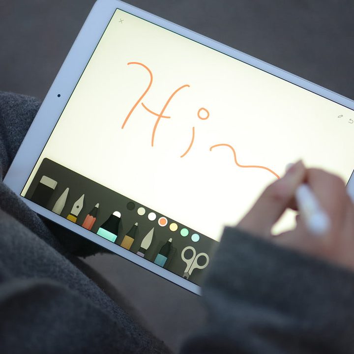 An iPad being used with an Apple Pencil. "Hi" is written on the screen.