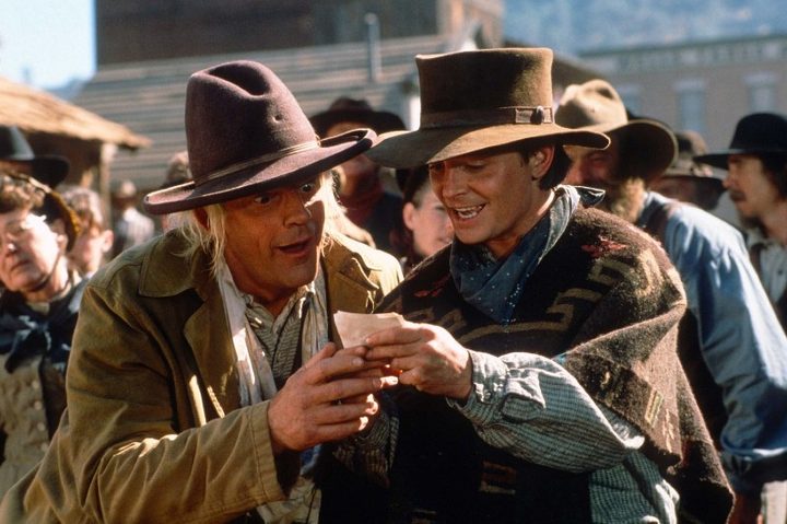 Marty McFly and Doc Brown stares at a piece of paper.