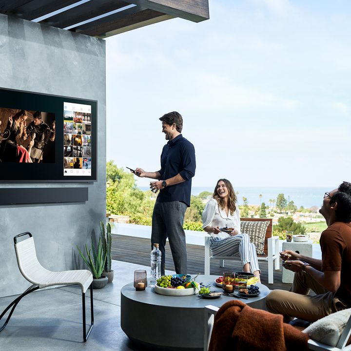 A family watching an outdoor TV.