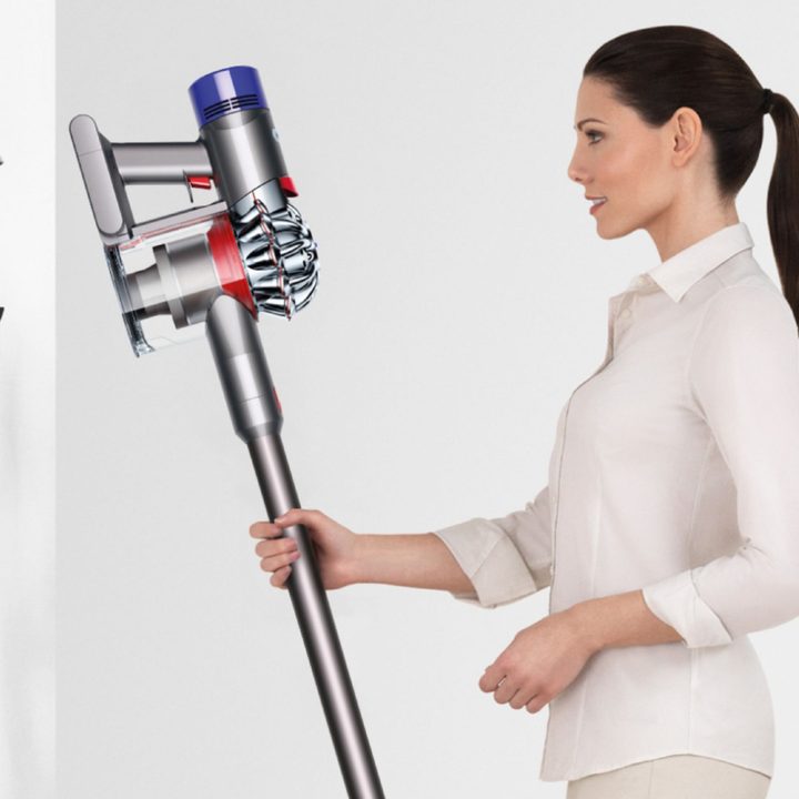 A woman holds a Dyson V7 Allergy Cordless HEPA Vacuum.