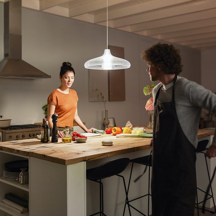 Two people standing in a kitchen lit by a Philips Hue light.