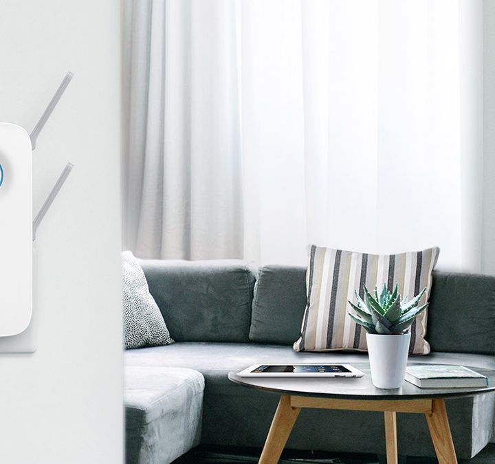 The TP-Link AC2600 Wi-Fi extender mounted on a wall in a ling room.