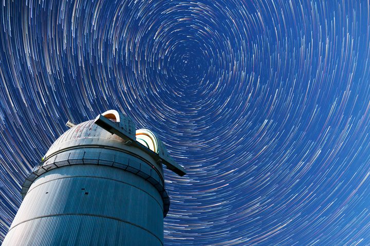 Astronomical observatory under the night sky stars. Blue sky with hundreds of stars of the Milky way. Timelapse in comet mode.
