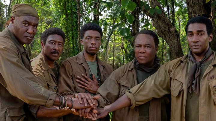 Five Black soldiers joining hands and looking at the camera in Spike Lee's Da 5 Bloods.