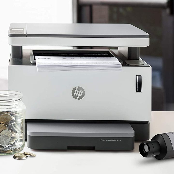 A printer sitting on a desk next to coins.