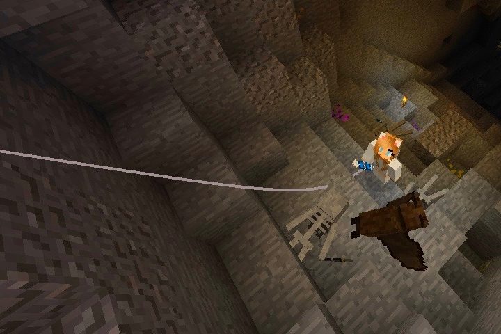 A minecraft character uses a grappling hook to climb out of the underground.