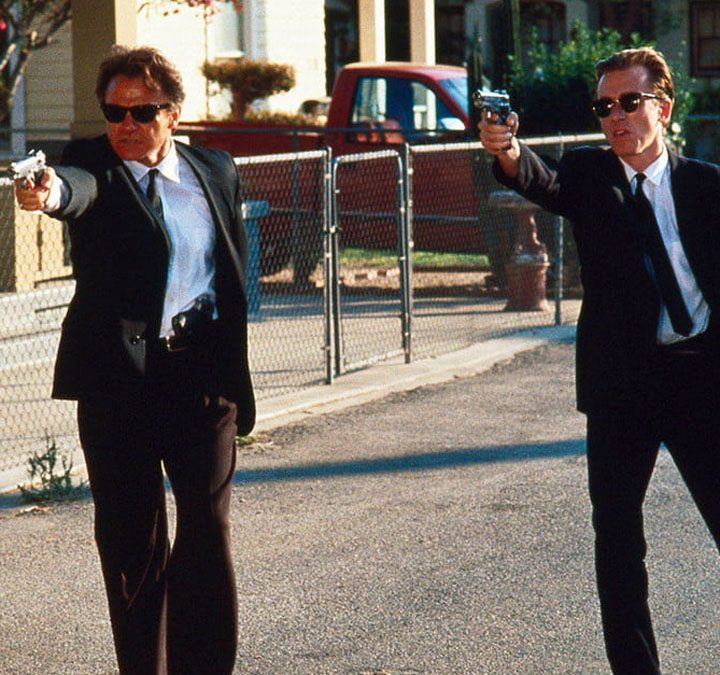 Harvey Keitel and Tim Roth as Mr. White and Mr. Orange aiming guns in the same direction in the film Reservoir Dogs.