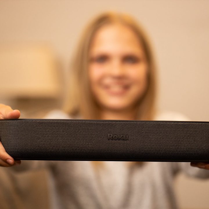 A woman holding a Roku Streambar.