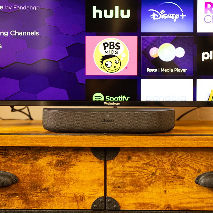 The Roku Streambar on a media console with a TV.
