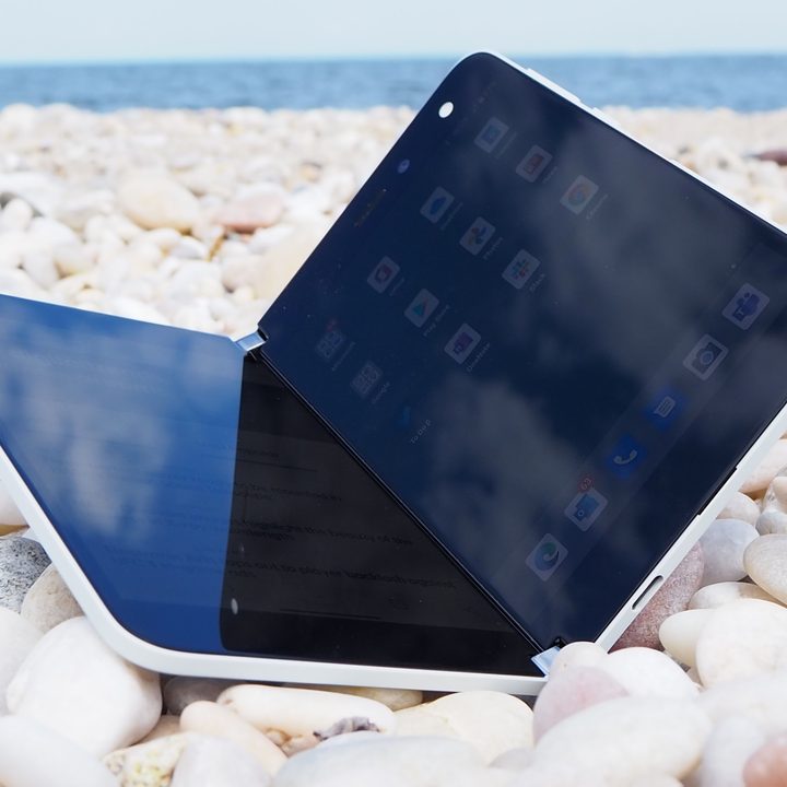 The Microsoft Surface Dup foldable smartphone placed on pebbles.